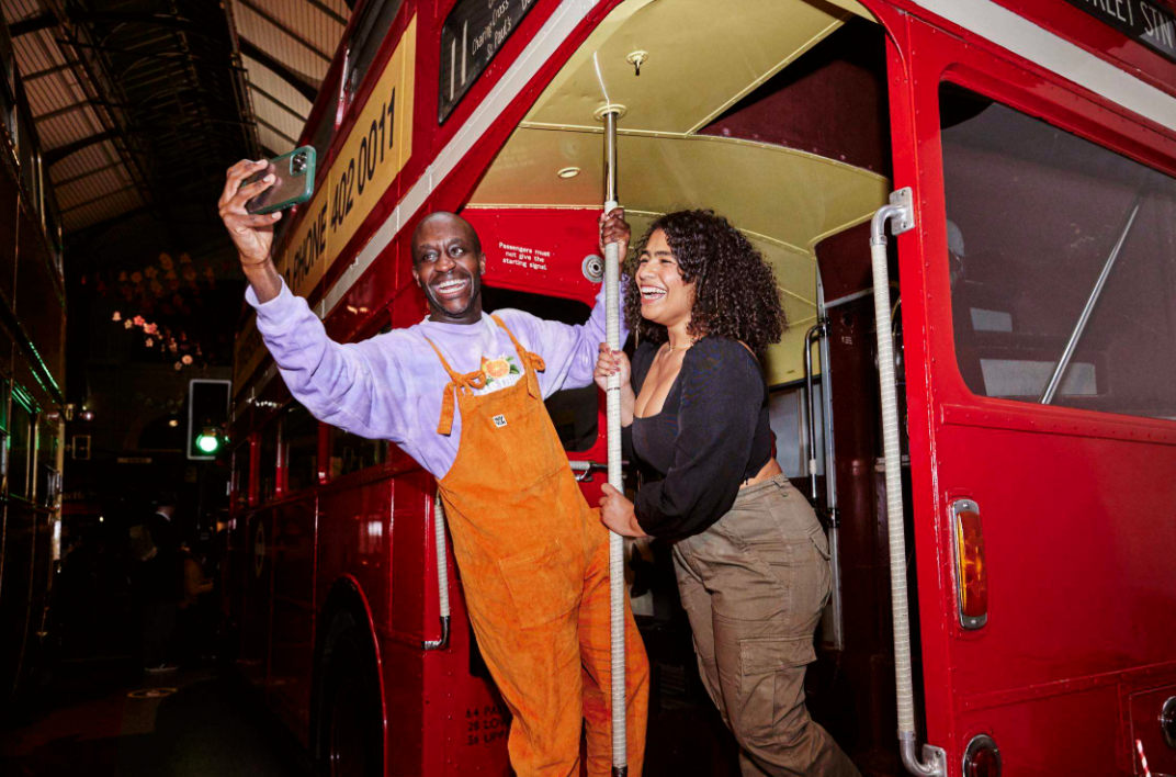 Two guests enjoying a Halloween event beside a vintage London bus
